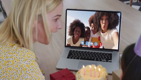 madre y hija caucásicas celebrando su cumpleaños mientras hacen una videollamada en una computadora portátil en casa