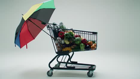 a colorful umbrella protects a shopping cart overflowing with fresh produce, showcasing the joy of grocery shopping and the importance of healthy eating.