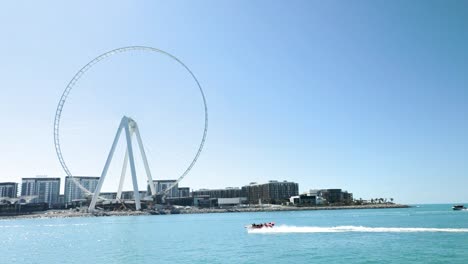 boat passing by dubai marina and ferris wheel in slow motion