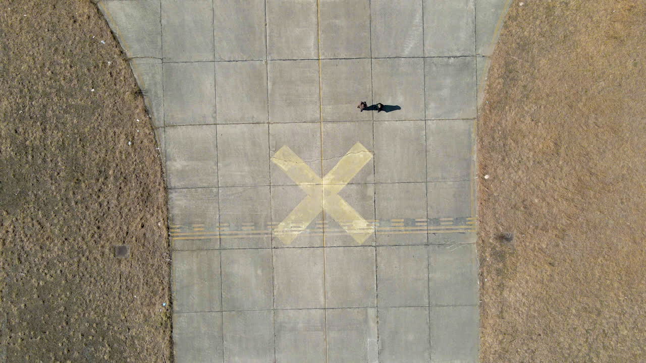 위에서 총격을 받는 사람들을 똑바로 내려다보는 공중 드론 영상, 사용하지 않는 오래된 비행장을 걷는 사람들