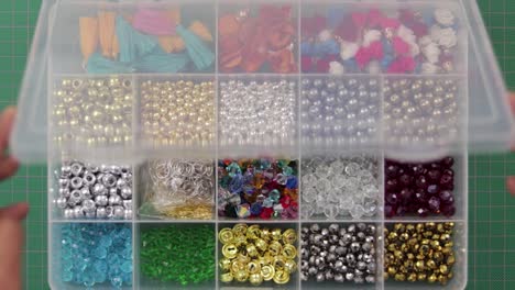 cuentas, piedras y joyas organizadas en una caja de plástico