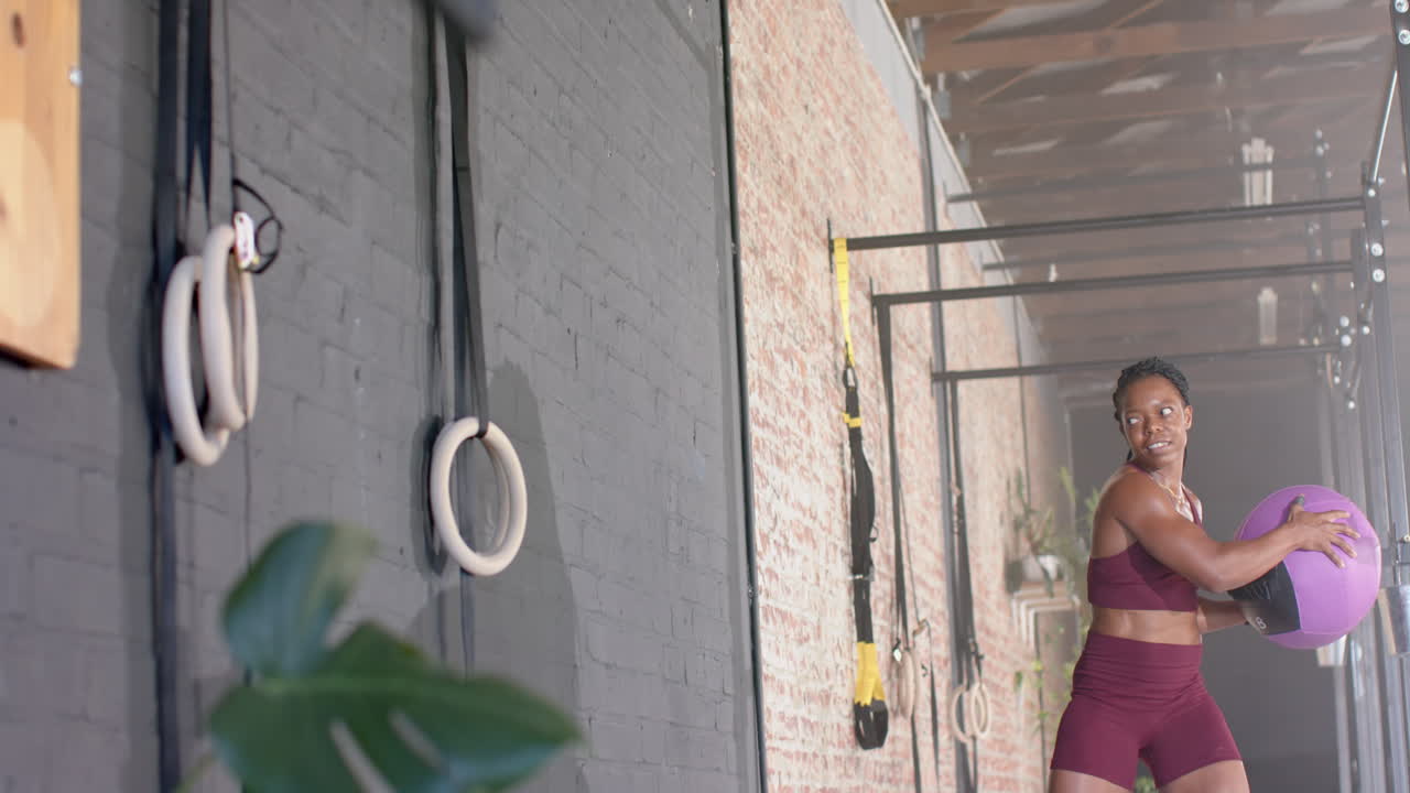 Exercising with medicine ball, woman training in gym for fitness workout, copy space