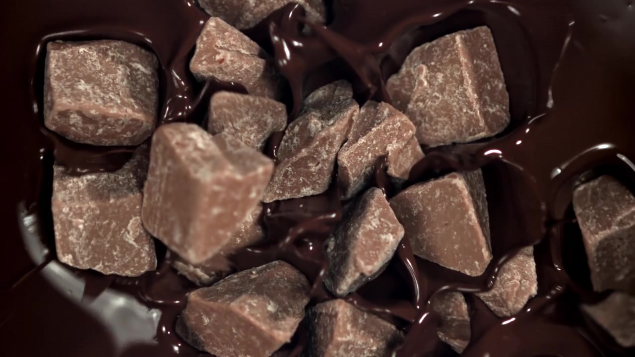 Cioccolato fuso che cola su pezzi di cioccolato al rallentatore