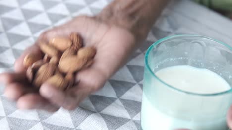 persona de edad avanzada que come almendras y bebe leche de almendras