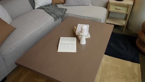 dolly-shot-of-a-coffee-table-decorated-with-white-books-and-a-white-candle