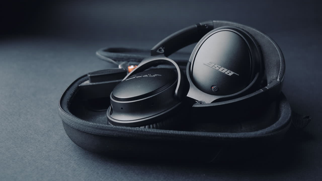 A product shot of black headphones on a black background, In a box. Camera movement  from right to left.