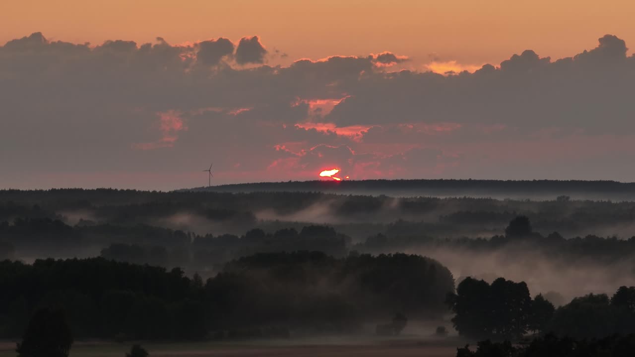 turbina de molino de viento aislada al atardecer en la cima de una colina con paisaje brumoso