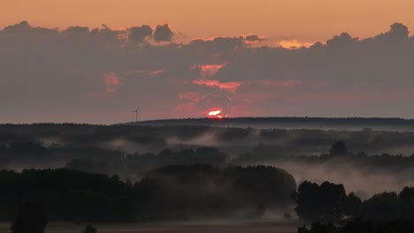 windmill turbine isolated at sunset on top of a hill with foggy landscape