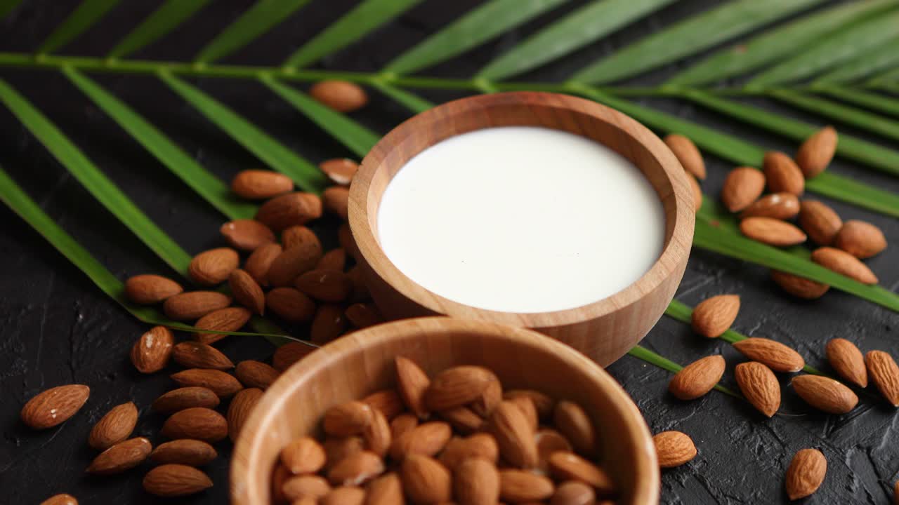 primer plano de almendras en tazón de madera y leche de almendras