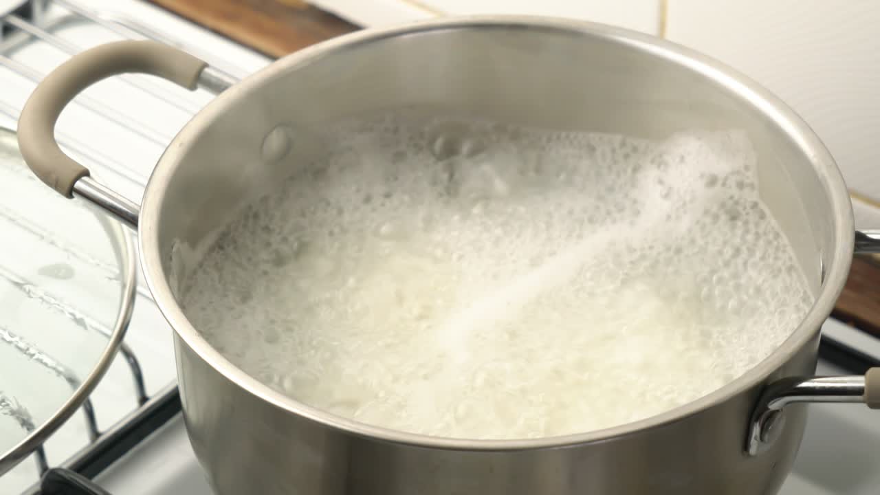 High angle view of opening cover metal pot of hot boiled rice.