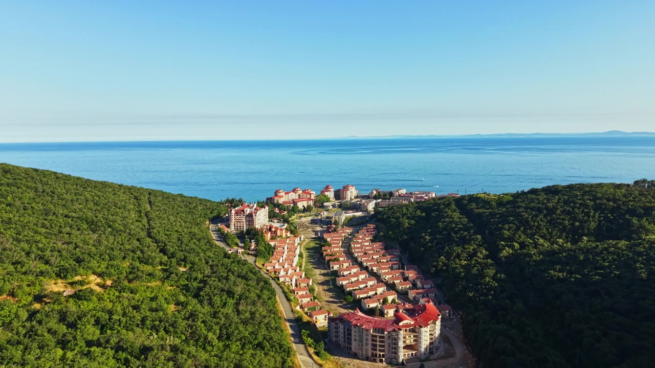 Città di Elenite dopo l'alluvione, mostra edifici e paesaggio sotto un cielo sereno e un mare blu alla luce del giorno.