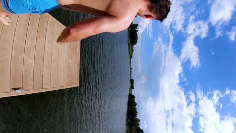toma de un joven saltando al agua en verano, tiro vertical, cámara lenta