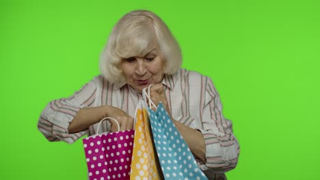 senior grandmother showing black friday inscription from shopping bag, smiling, rejoicing discounts