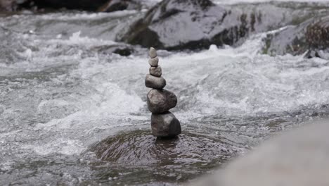 rock cairn, pile of stones stacked on top of each other on rocky river, slow motion