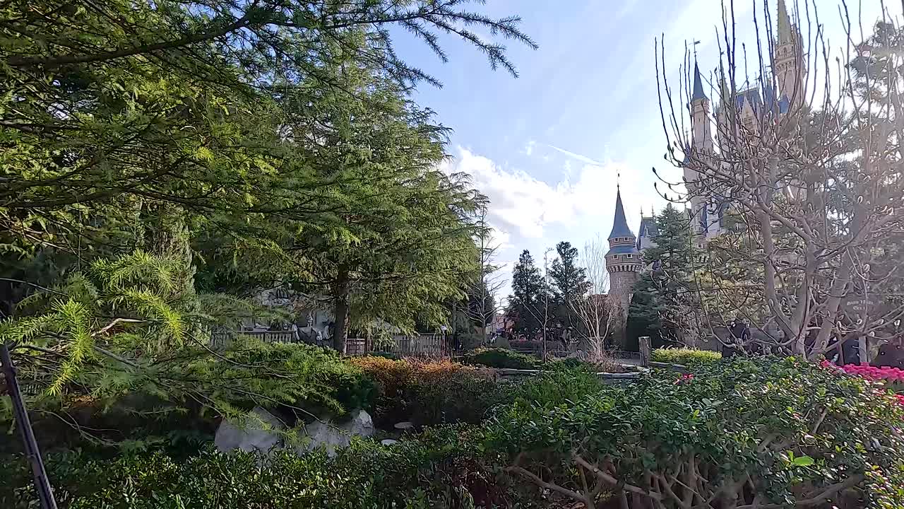 A serene view of lush gardens and a castle under bright daylight at Tokyo Disneyland