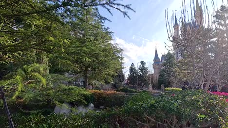 a serene view of lush gardens and a castle under bright daylight at tokyo disneyland