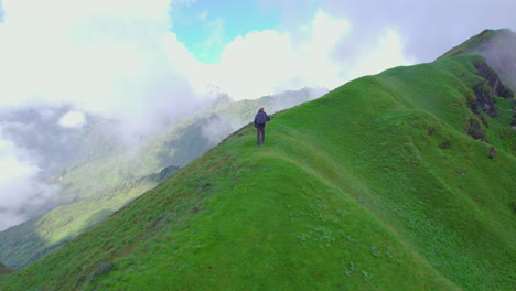 nepali solo trekker walks green hills of nepal carrying a stick, drone shot, cloudy sky, scenic beauty landscapes, heavenly nature