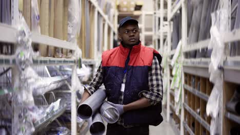 workman walks with water pipes in plumbing or hardware store, slow motion