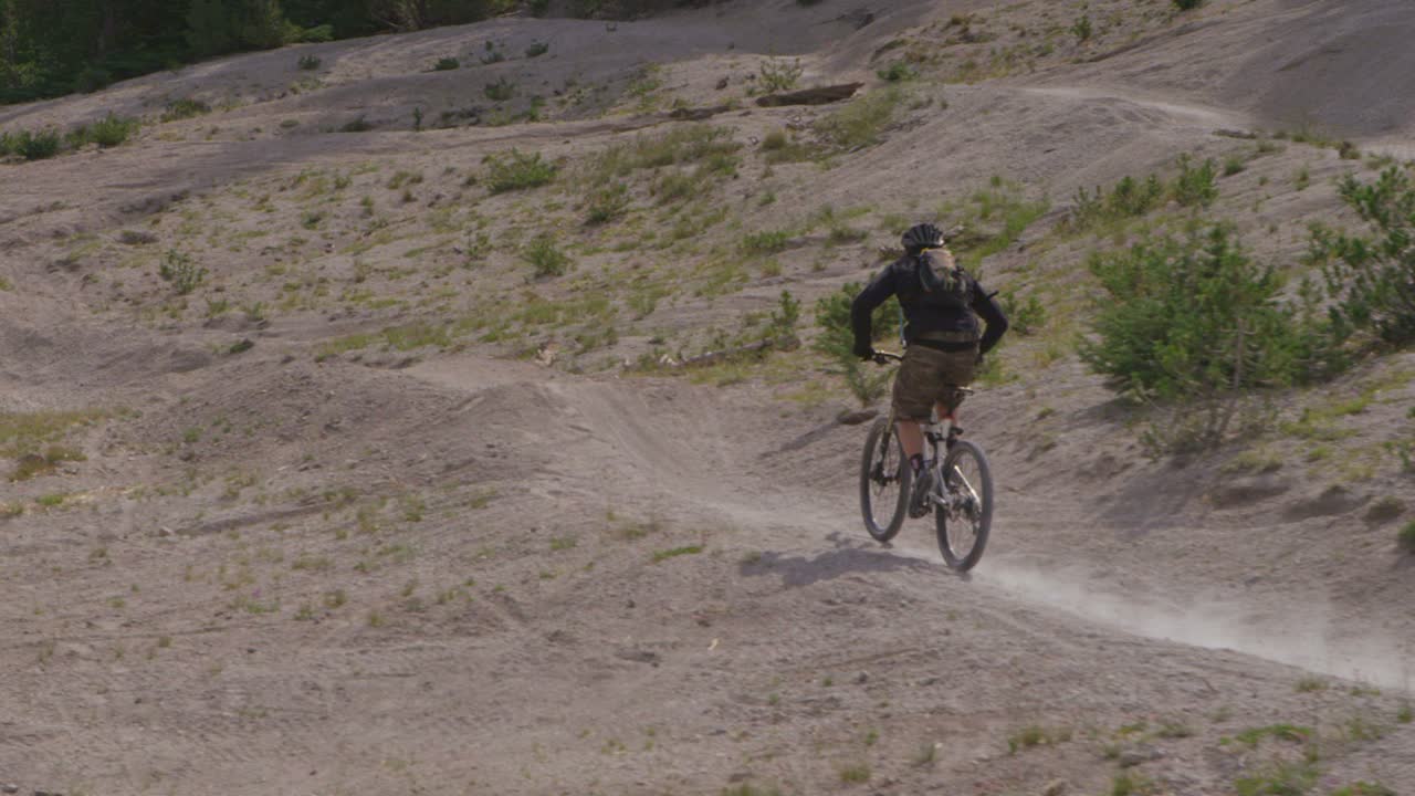 un ciclista de montaña da un salto en un camino cerca de un bosque