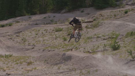 a mountain biker does a jump on a path near a forest