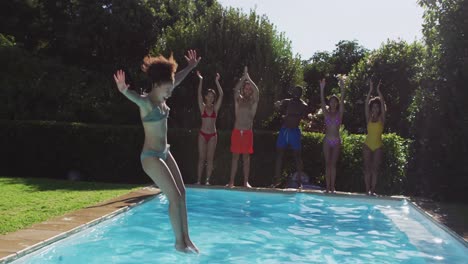 un grupo diverso de amigos divirtiéndose saltando a una piscina