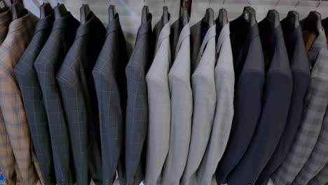 a diverse selection of men's suits hangs neatly in a store, showcasing different colors and designs ideal for formal events during the fall season