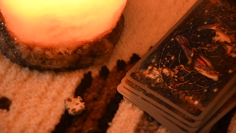 close up of a man's hand taking tarot cards one by one, near some stones and a salt lamp, on a carpet