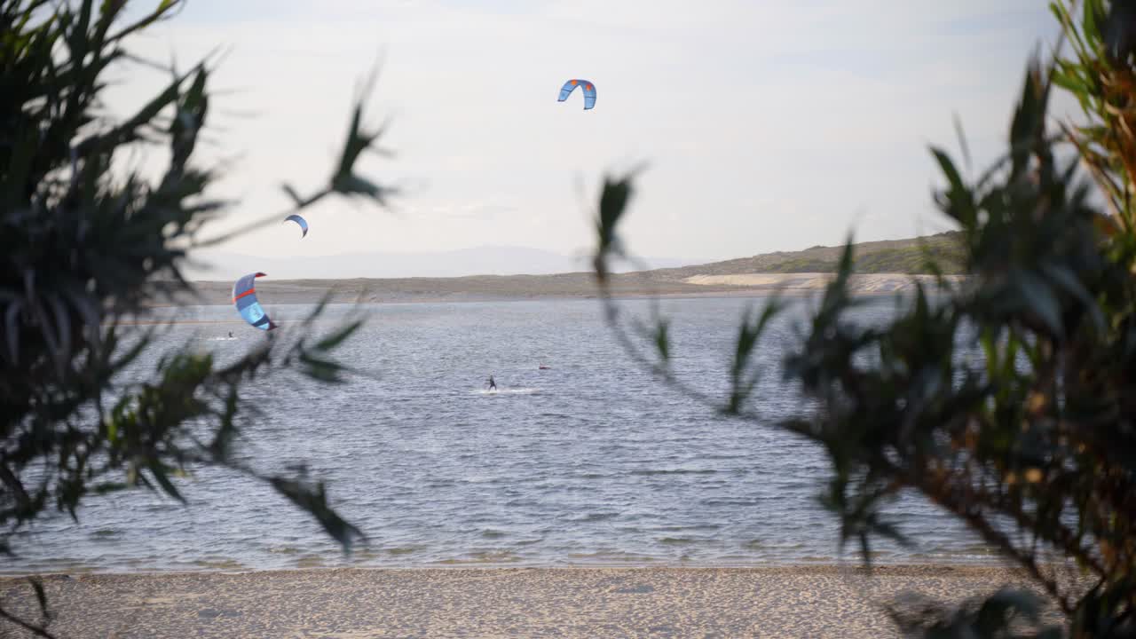 turistas haciendo kitesurf en un día ventoso en una playa de lagoa da albufeira en portugal