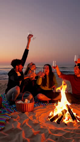 group of friends enjoying a beach bonfire at sunset