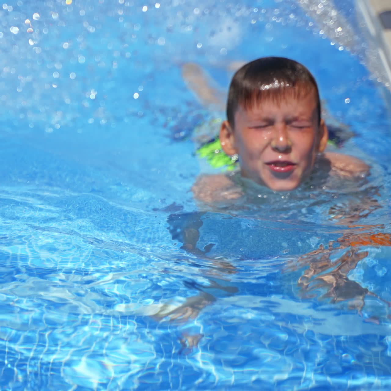 Boy in the pool outdoors. Cute boy showing his mother his underwater swimming in summer. Teenager in the swimming pool. Close-up.
