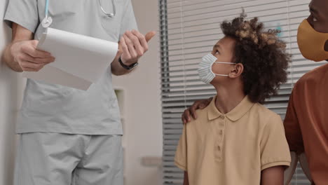 niño africano siguiendo al médico en la oficina