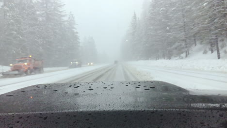 a truck drives through a snowstorm as snow plows pass and the windshield wipers work frantically to keep the windshield clear