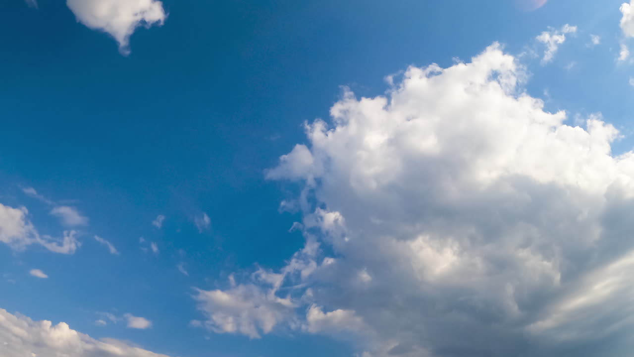 Amazing azure skies with white clouds slowly floating in the air. Cloudscape lit with bright summer sun. Low angle view timelapse.