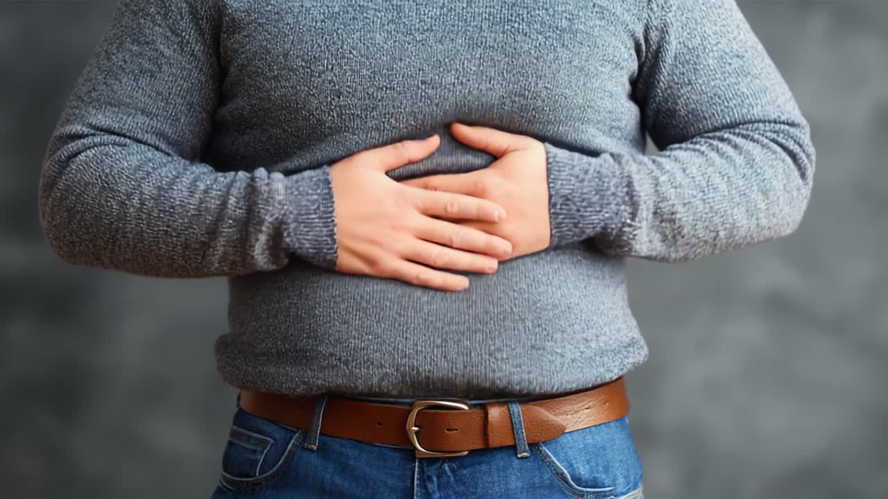 Persona che si tiene lo stomaco con le mani in un maglione grigio: una prospettiva ravvicinata sul disagio e la cura per la digestione e il benessere.