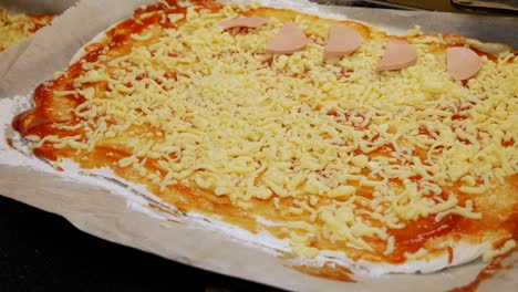 la cocinera casera está poniendo una salchicha fresca en la pizza casera