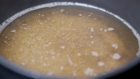 Fresh-golden-bone-broth-simmering-in-pan,-close-up