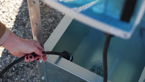 Toma-Giratoria-De-Una-Mujer-Recogiendo-Un-Cable-Eléctrico-Para-Un-Panel-Solar