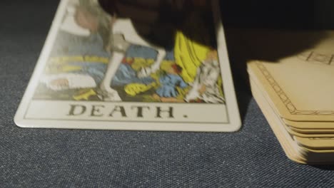 disparo de cerca de la persona que da la lectura de la carta del tarot colocando la carta de la muerte en la mesa 1