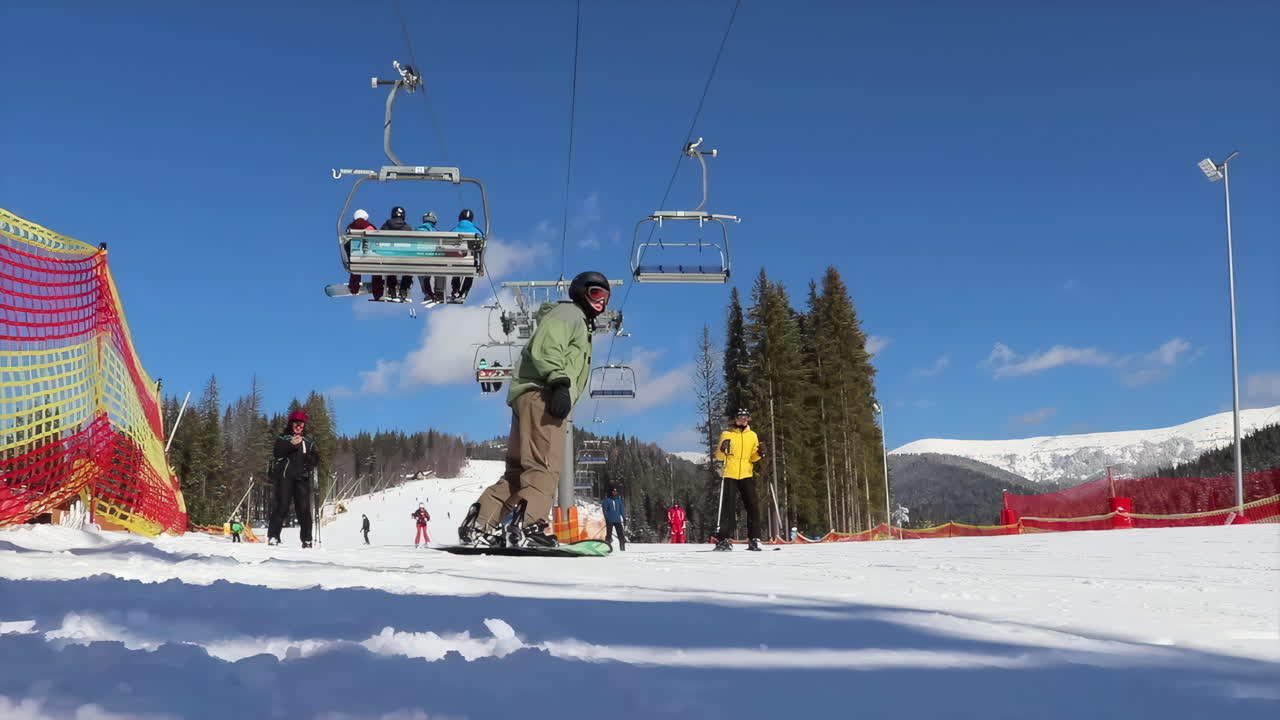 Bukovel, Ukraine - January 20, 2020: People skiing under a ski lift at a resort on a sunny day