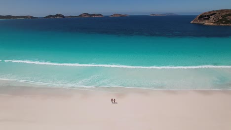 4k drone video of a couple running from the the bright blue ocean towards their camper van on lucky bay beach in the cape le grand national park near esperance in south west australia