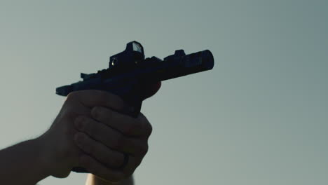 close-up of man firing pistol repeatedly with sun flare