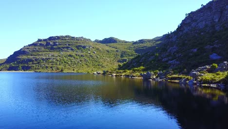 Vista-Aérea-Sobre-El-Lago-En-Las-Montañas-Durante-El-Verano