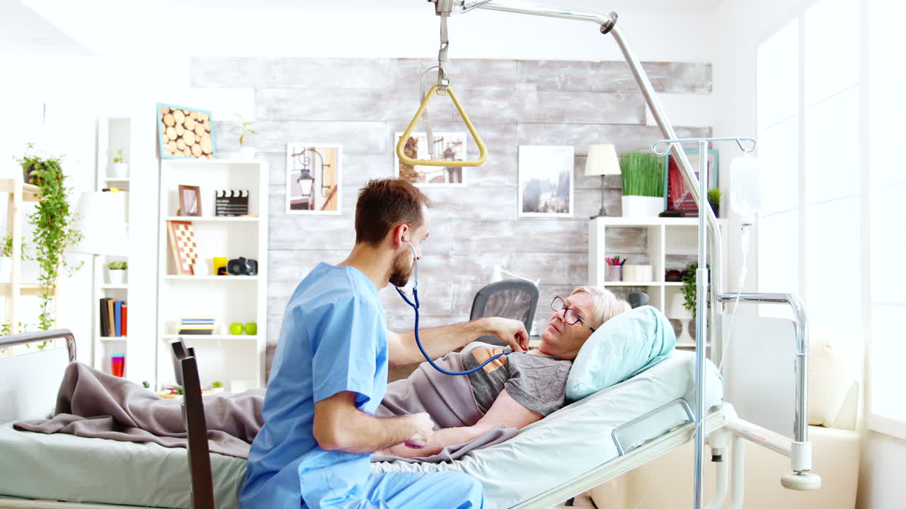 enfermera masculina comprobando los latidos del corazón de una anciana enferma acostada en una cama de hospital