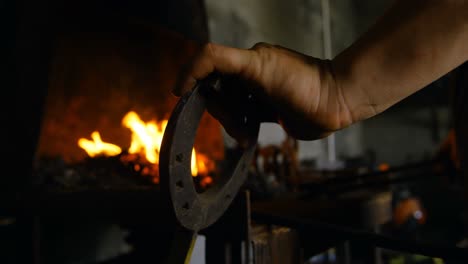 Female-metalsmith-heating-horseshoe-in-fire-4k