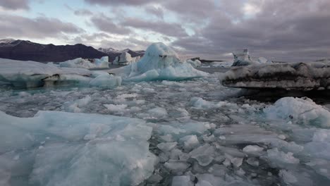 Cinematic-low-aerial-backwards-away-from-iceberg-over-ice-floes-in-the-arctic
