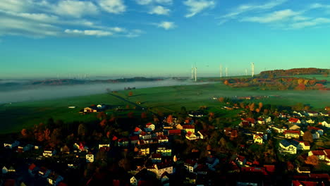 aerial view of a village in autumn with wind turbines and fog