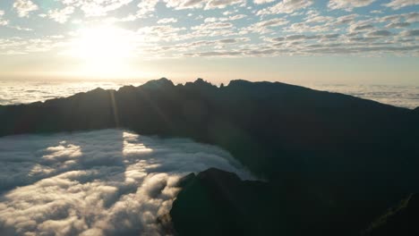 bright sun shines into cloud filled valley with tall mountains in madeira