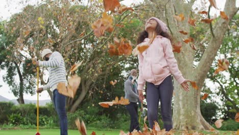 video of happy african american daughter throwing leaves with father and grandfather in garden