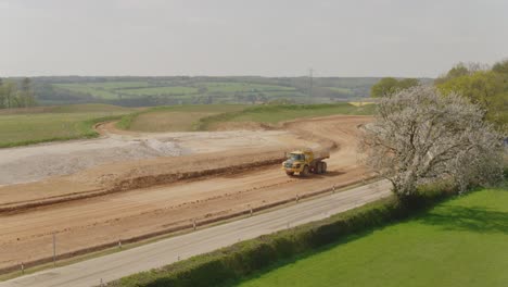 un camión de descarga hace su camino a velocidad a lo largo de una pista de sitio de construcción