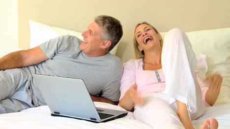 en la cama con una pareja de computadora portátil
